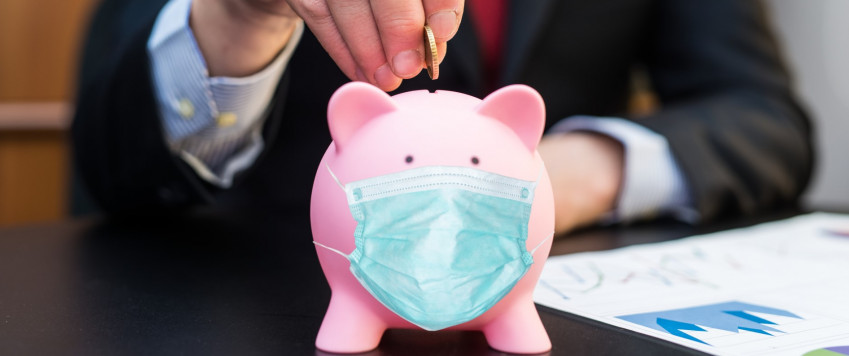 Male putting money in a piggy bank, illustrative picture