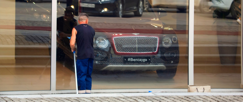 Window cleaner looks inside luxury car shop, illustratice picture