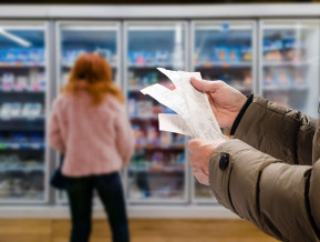 Minded man viewing receipts in supermarket and tracking prices